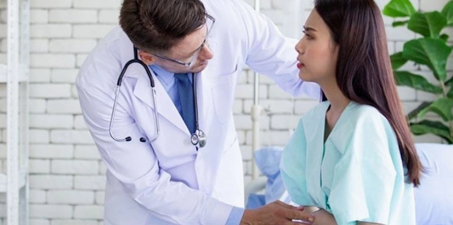 Một người đang ôm bụng đau và phân vân khi nào cần đi gặp bác sĩ