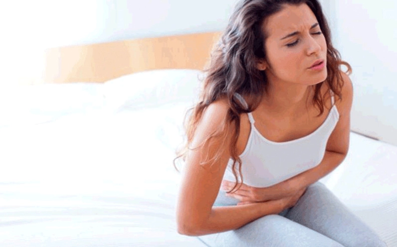 Một người phụ nữ đang ôm bụng dưới vì cơn đau bụng kinh do bệnh lý